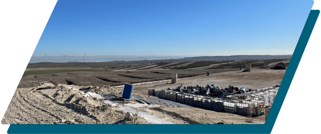 Contenedores de residuos en un entorno agrícola con energías renovables en el fondo.